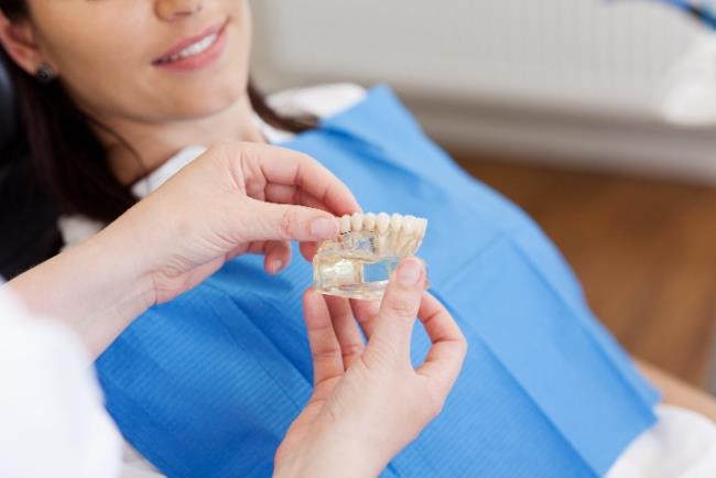 רופא שיניים מתאים דגם של כתר בסריקה דיגיטלית לפיה של אישה